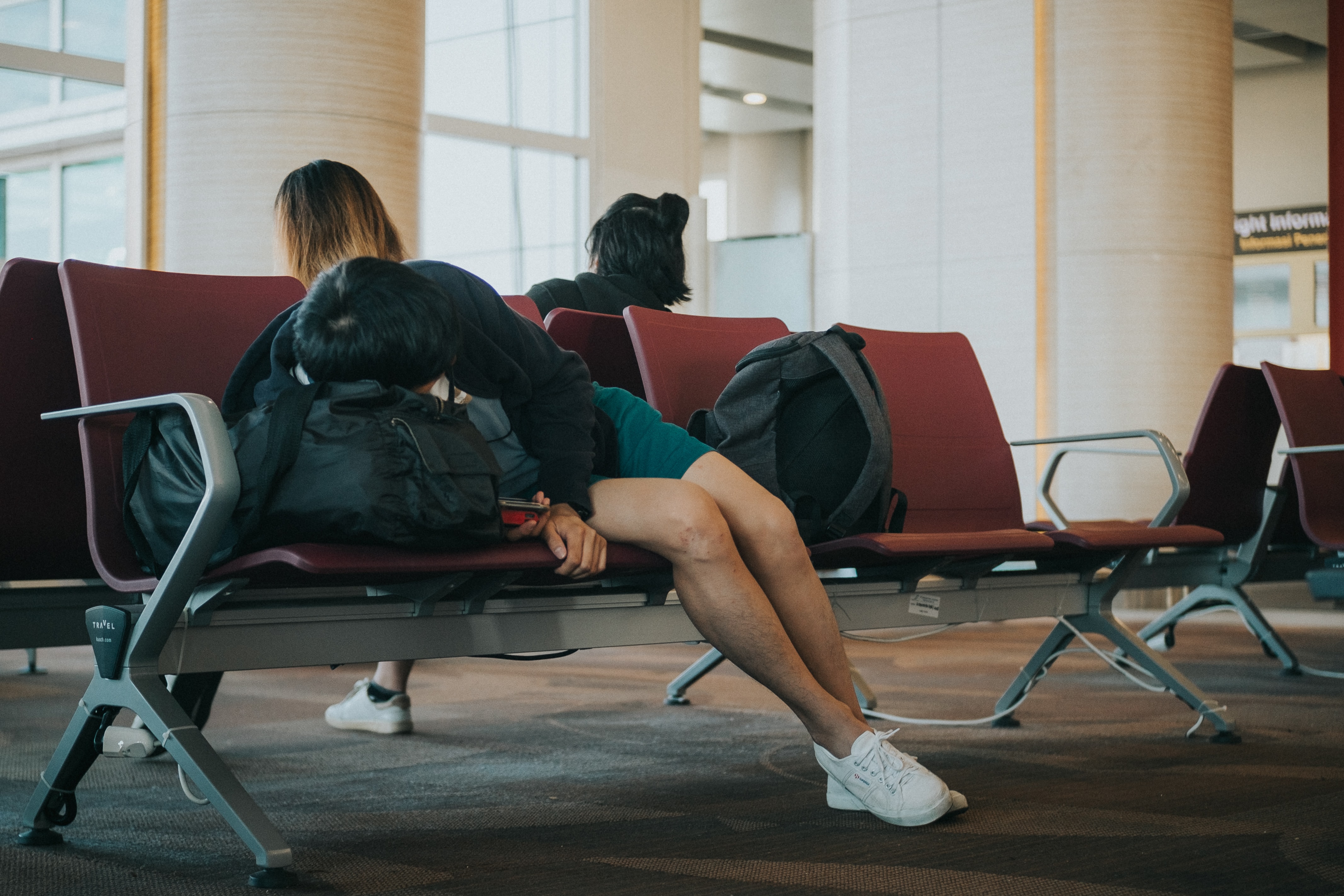Foto door Joyce Romero op Unsplash. Slaap inhalen op de luchthaven.