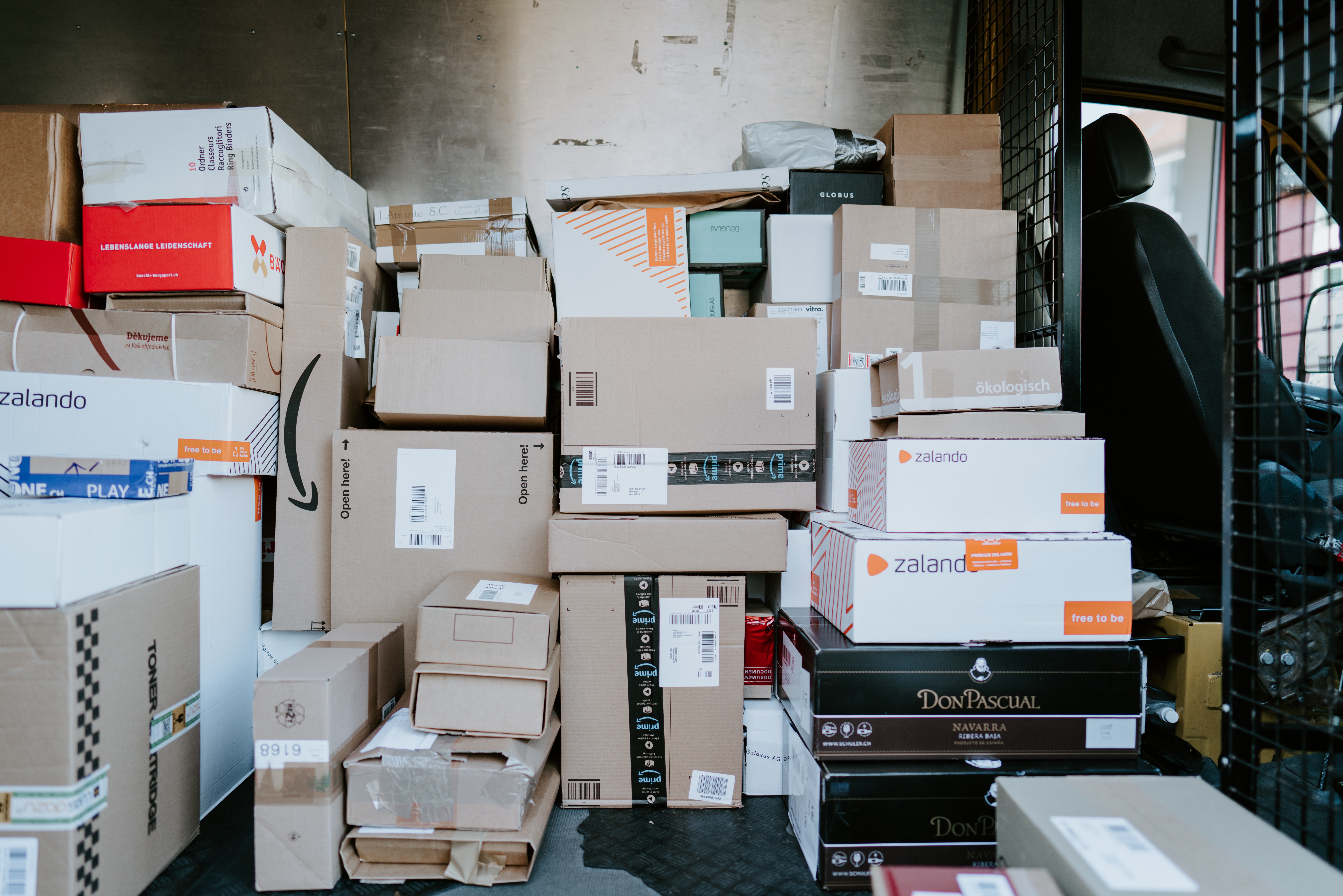 Foto door Claudio Schwarz op Unsplash. Pakjes in de laadruimte van een koerier.